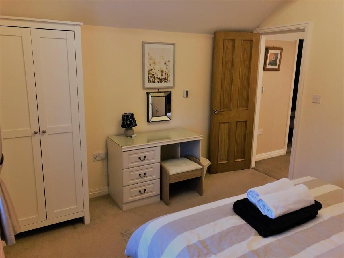 Ein Schlafzimmer mit Bett, Schreibtisch, Stuhl und Kleiderschrank.