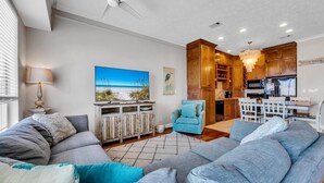 Un salon moderne avec un canapé gris, un fauteuil bleu et un meuble en bois.