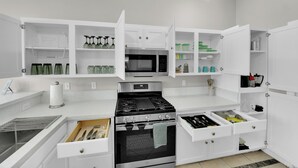 A modern kitchen with white cabinetry, a stainless steel stove, and a microwave. - Henderson escape+ mini golf +peaceful stay (Henderson)