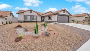 A residential area with a house featuring a tiled roof, a garage, and a landscaped garden with cacti and pebbles. - Henderson escape+ mini golf +peaceful stay (Henderson)