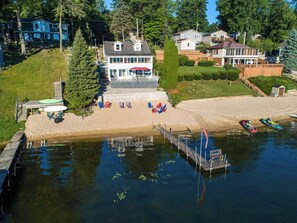 Una propiedad frente al lago con muelle, playa de arena y una casa con amplio balcón.