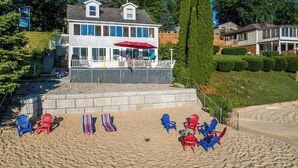 Ein Strandgrundstück mit überdachter Terrasse, mehreren Adirondack-Stühlen und einer Flagge.