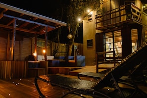 Un espace de détente extérieur avec des meubles en bois, une piscine et un bâtiment doté de nombreuses fenêtres et de balcons.