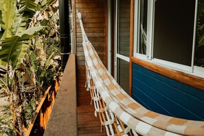 A wooden bench with a hammock on a porch. - Surfway Ilha do Mel (Paranaguá)