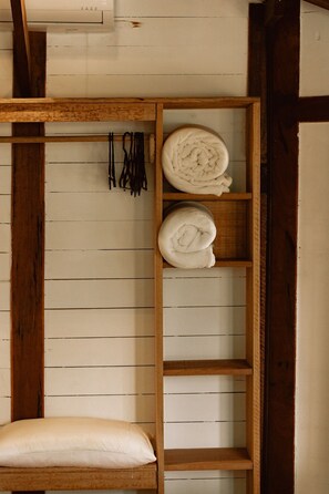 A wooden shelf unit with rolled towels and a pillow against a paneled wall. - Surfway Ilha do Mel (Paranaguá)