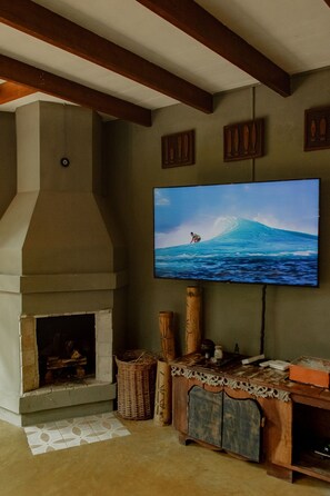A living room with a fireplace, a television mounted on the wall, and a wooden cabinet. - Surfway Ilha do Mel (Paranaguá)