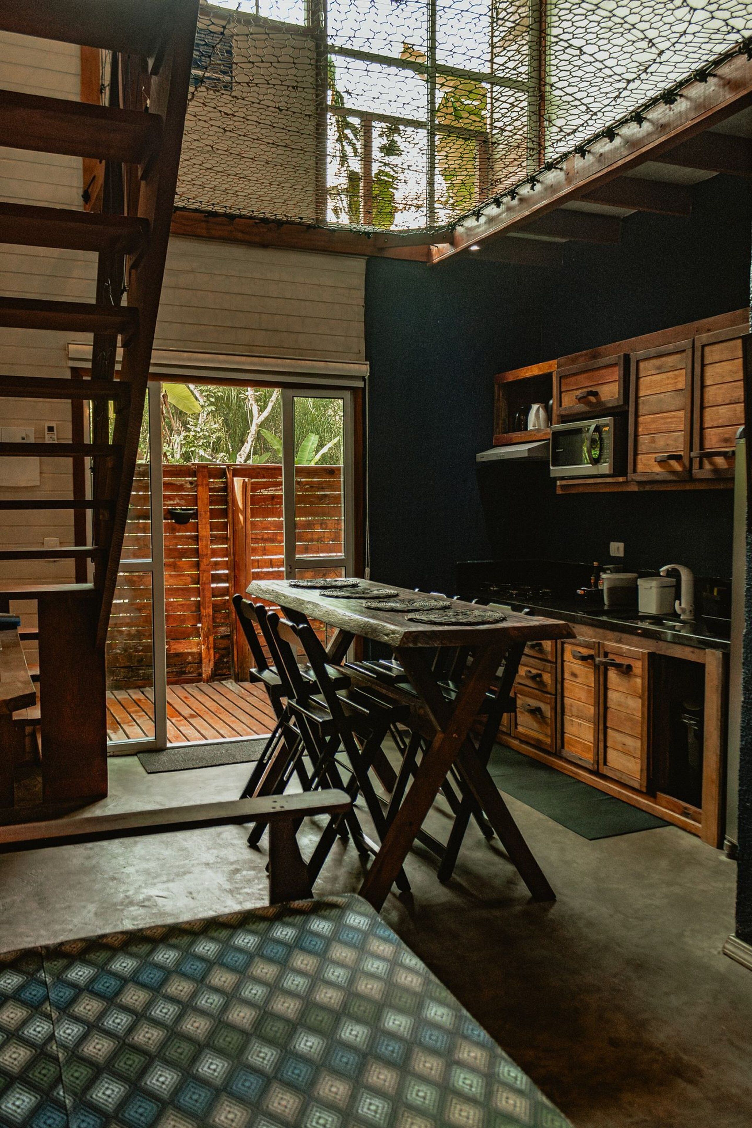 A kitchen with wooden cabinets, a dining table, and a staircase leading to an outdoor area.