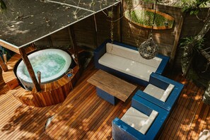 A wooden deck with a hot tub, blue and white lounge seating, and hanging plants. - Surfway Ilha do Mel (Paranaguá)