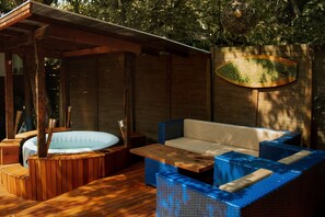 Una terraza de madera con un jacuzzi, un sofá y una mesa.