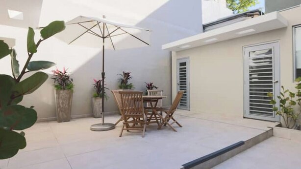 A patio with a table and chairs, surrounded by potted plants and a large umbrella. - Old San Juan Guesthouse.Free Parking, Rooftop & Generator – Casa Terra Porto #8 (San Juan)