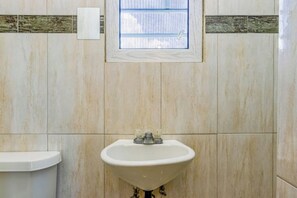 Une salle de bain avec un lavabo, des toilettes et une fenêtre.