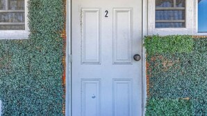 A white door with the number 2, surrounded by a wall covered in green foliage. - Beach House Walk To The Beach #2

 (San Juan)
