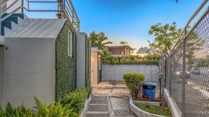 A narrow pathway leading to a building with a green wall and a fence on one side. - Beach House Walk To The Beach #2

 (San Juan)