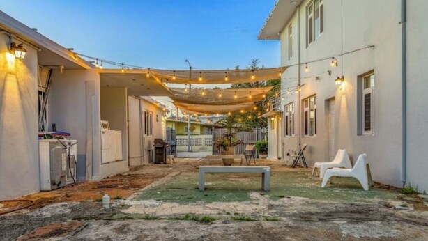 A courtyard with a bench, outdoor seating, and string lights. - Beach House Walk To The Beach #2

 (San Juan)
