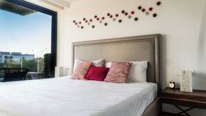 Ein Hotelzimmer mit einem großen Bett, einem Kopfteil mit Perlenstickerei und einer Wanddekoration in Herzform.