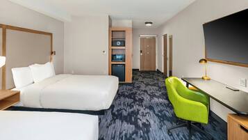 Habitación de hotel con cama, escritorio, silla, televisor y minibar.