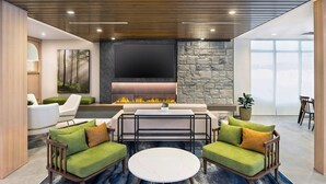 Ein modernes Wohnzimmer mit Kamin, grünen Sofas, einem runden Couchtisch und einer Wand mit Steinverkleidung.