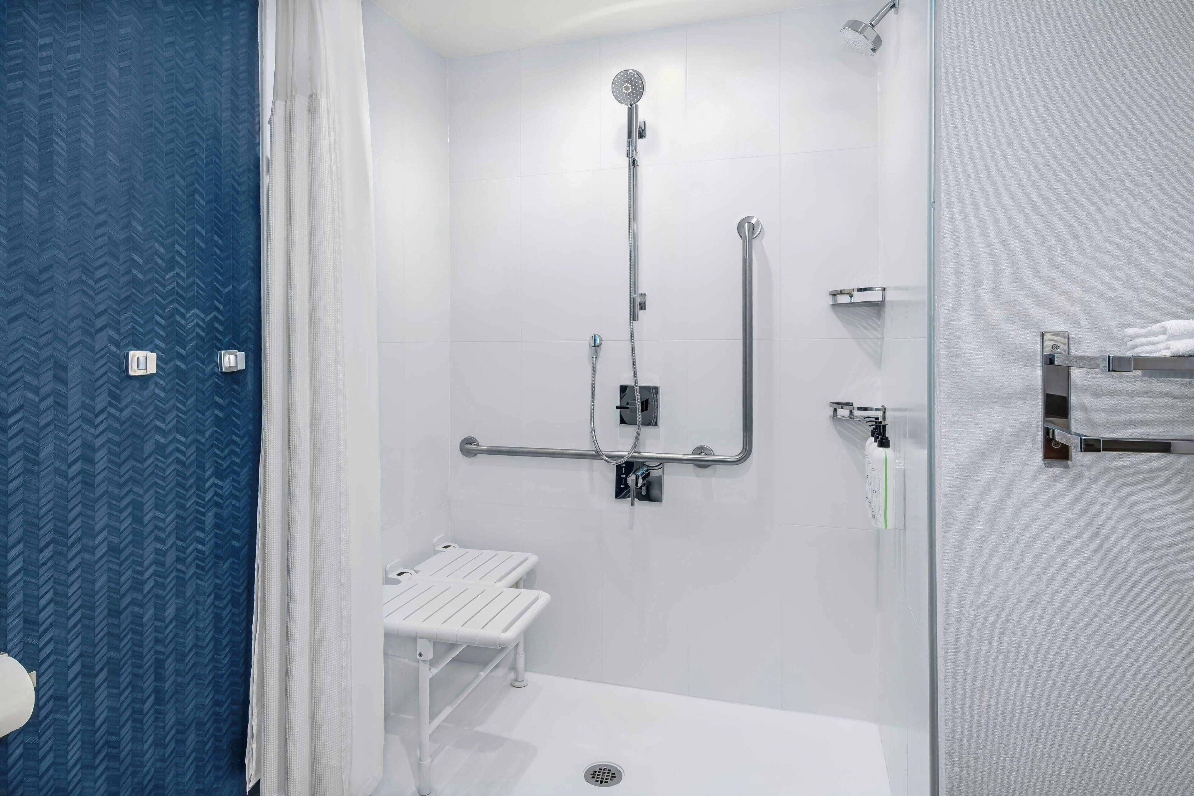 A modern bathroom with a shower, toilet, and a small bench.