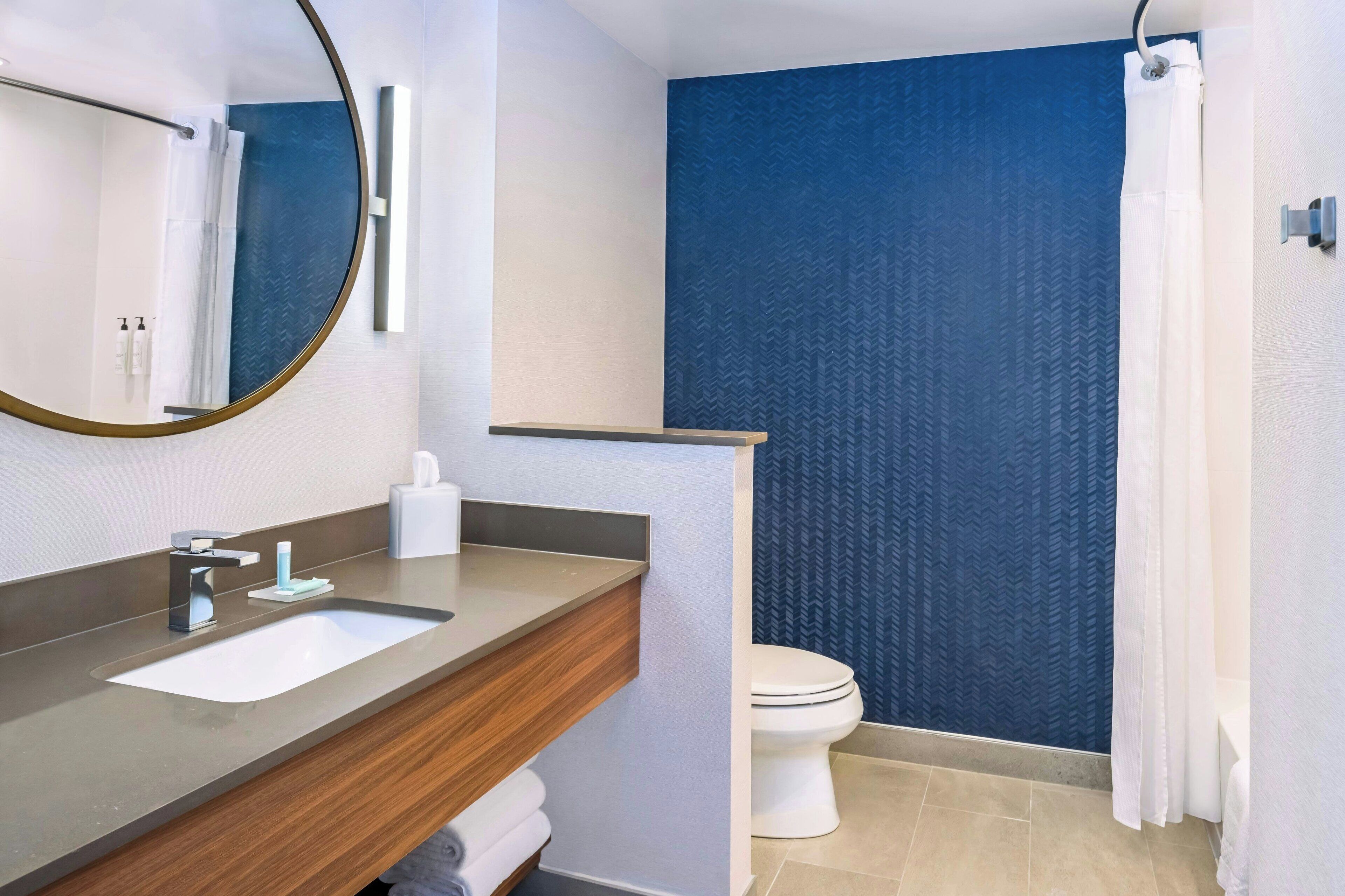A modern bathroom with a sink, mirror, and toilet.