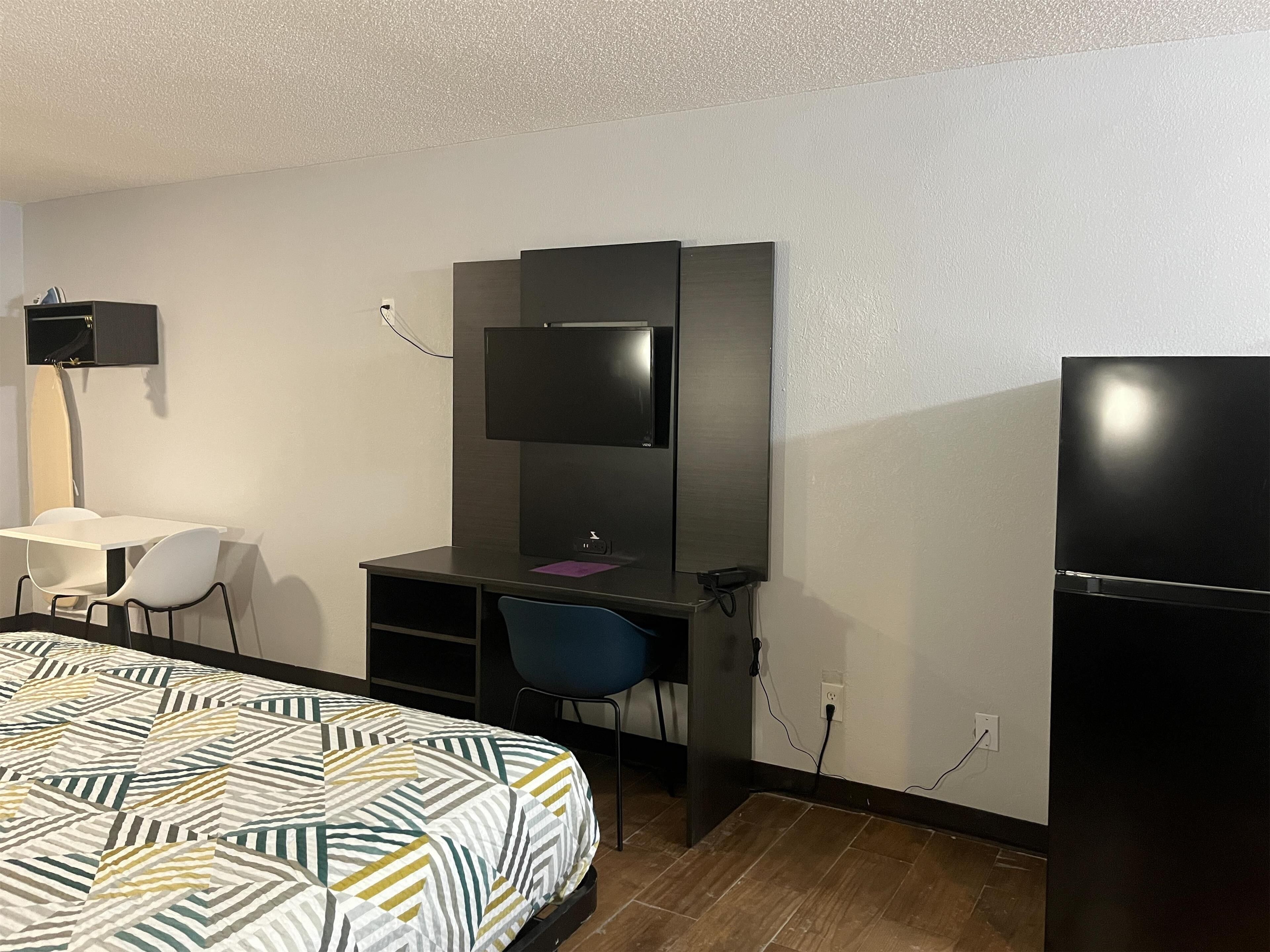 A hotel room with a bed, a desk, a chair, a TV, and a wardrobe.