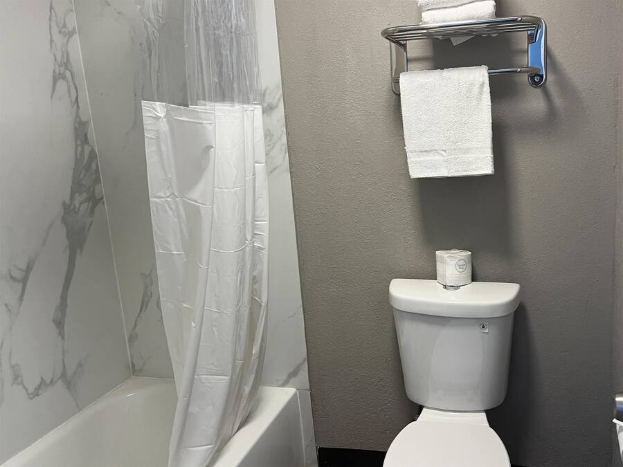 Un baño con cortina de ducha, inodoro y toallero.