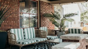 Un espace patio aménagé avec des meubles en osier, une plante en pot et une table en pierre.