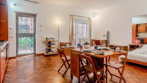 A dining area with a table set for four, a kitchen with wooden cabinets, and a bed with a white comforter.