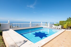 A rectangular swimming pool with a blue star design, surrounded by a white fence and a patio area with white furniture. - Charming Getaway in El Sauzal Enjoy Comfort Nature and a Private Pool (Sauzal)