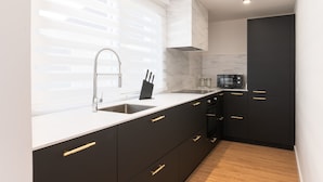 Une cuisine moderne avec un plan de travail blanc, des meubles de rangement noirs et un évier en acier inoxydable.