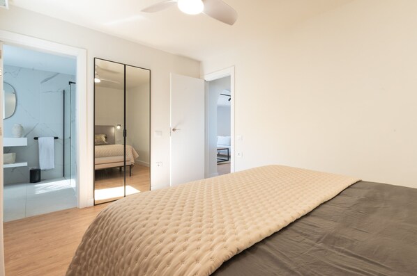 Ein Schlafzimmer mit Bett, Kleiderschrank und einem durchgegangenen Tür sichtbaren Badezimmer.