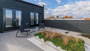 Un edificio moderno con un patio attrezzato con due sedie e un piccolo giardino.