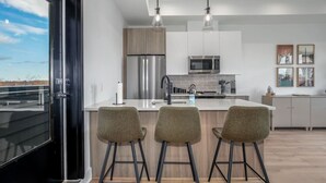 Una cucina moderna con isola centrale, elettrodomestici in acciaio inossidabile e vista attraverso una porta in vetro.