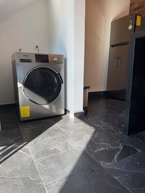 Compact laundry room with a front-loading washing machine and refrigerator.