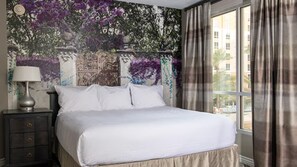 En snyggt bäddad säng i ett hotellrum med utsikt över byggnaderna utanför.