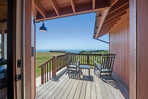 A wooden deck with a railing, a table, and two chairs.