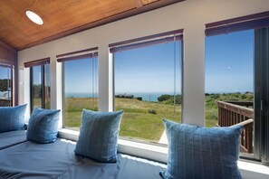 A room with large windows, a wooden ceiling, and a view of the sea.