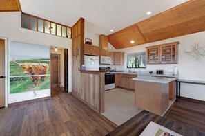 A modern kitchen with wooden cabinets, a central island, and a large window.