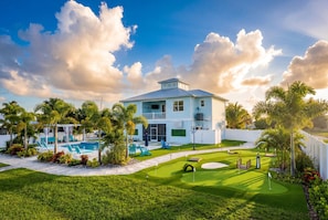 A two-story house with a swimming pool, a well-maintained lawn, and a golf course.