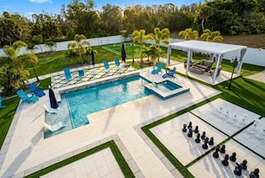 A swimming pool with lounge chairs and a covered seating area. - 3 bed 2 bath Beach House near Boca Grande with Pool + Sauna + Spa + Mini Golf (Placida)