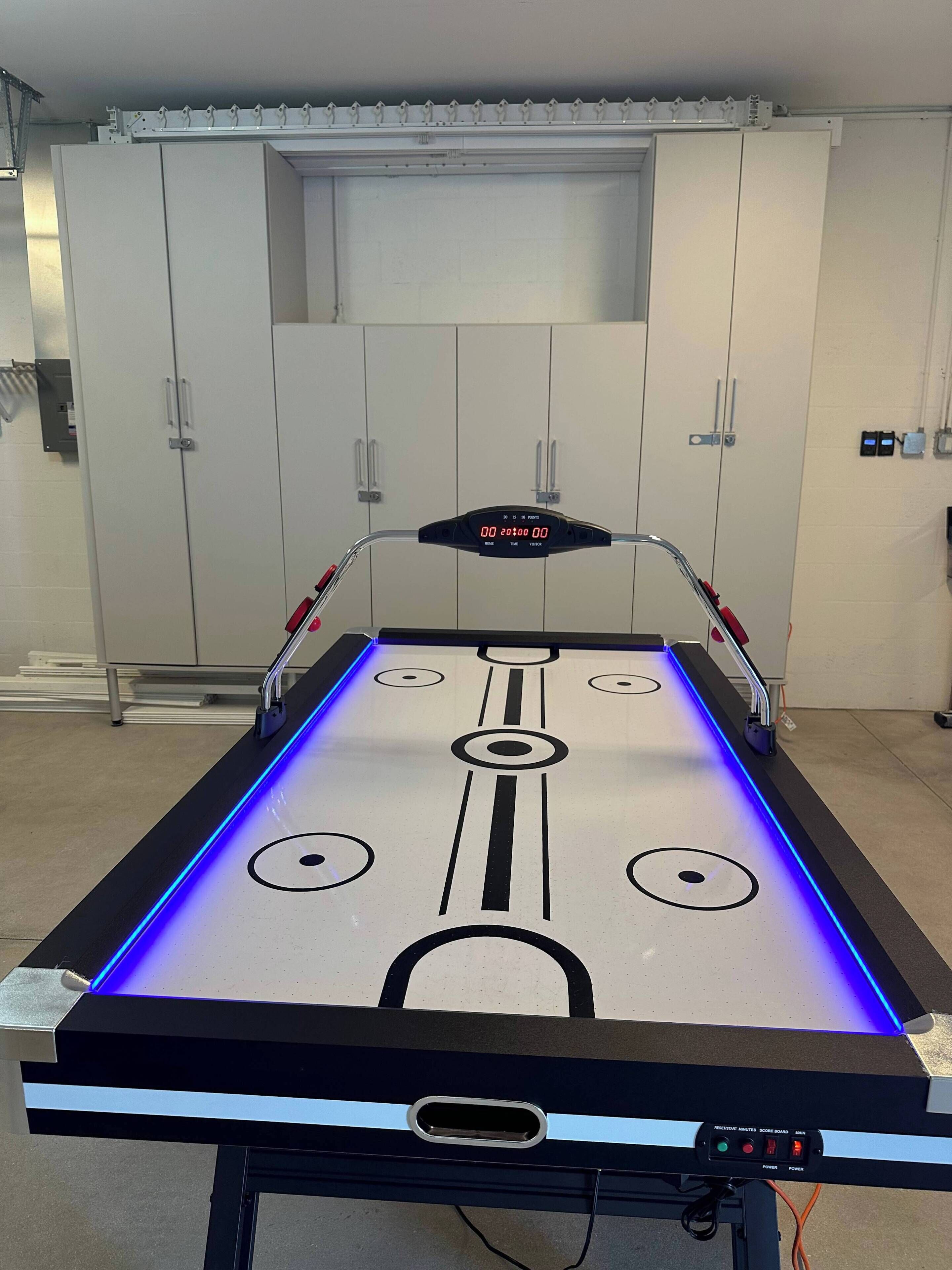 Un tavolo da shuffleboard con illuminazione a LED e indicazioni del punteggio.