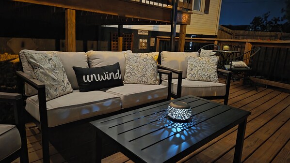 A wooden deck with a black table and a white lamp.