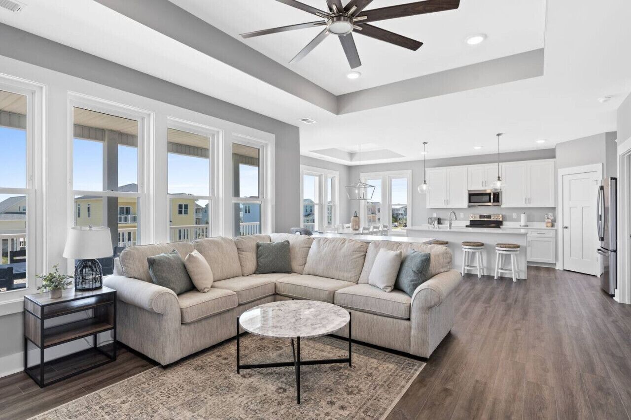 A spacious living room with a sectional sofa, a round coffee table, and a ceiling fan.