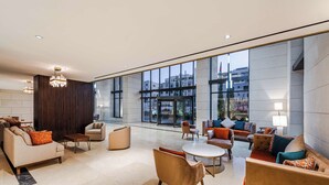 A spacious lobby with modern furniture, large windows, and a view of the city. - Doubletree By Hilton Amman Hotel & Residences (Amman)