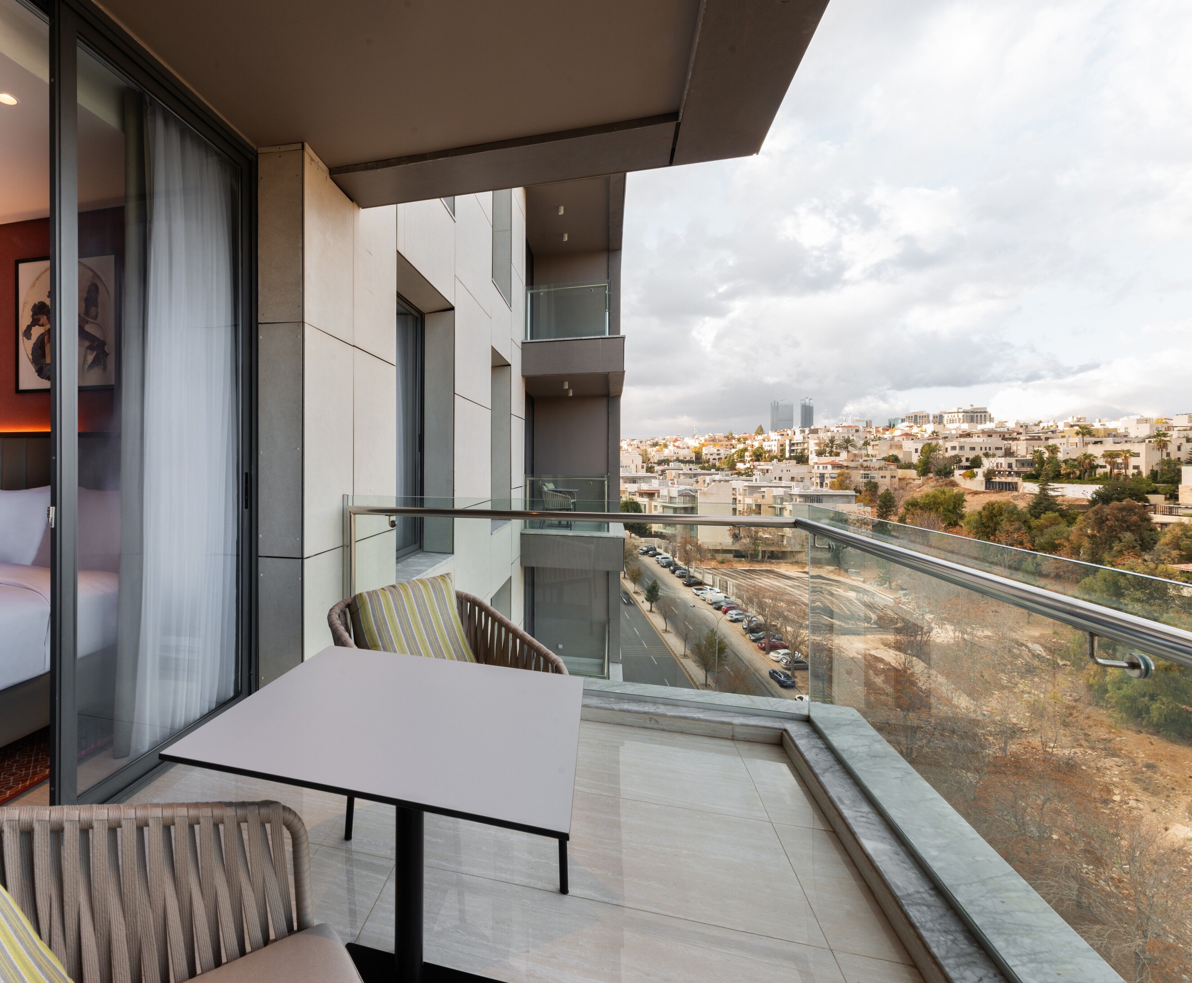A balcony with a glass railing, a sofa, and a table.