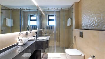 Une salle de bain moderne avec une douche à parois de verre, un grand miroir, un lavabo en marbre et des toilettes.