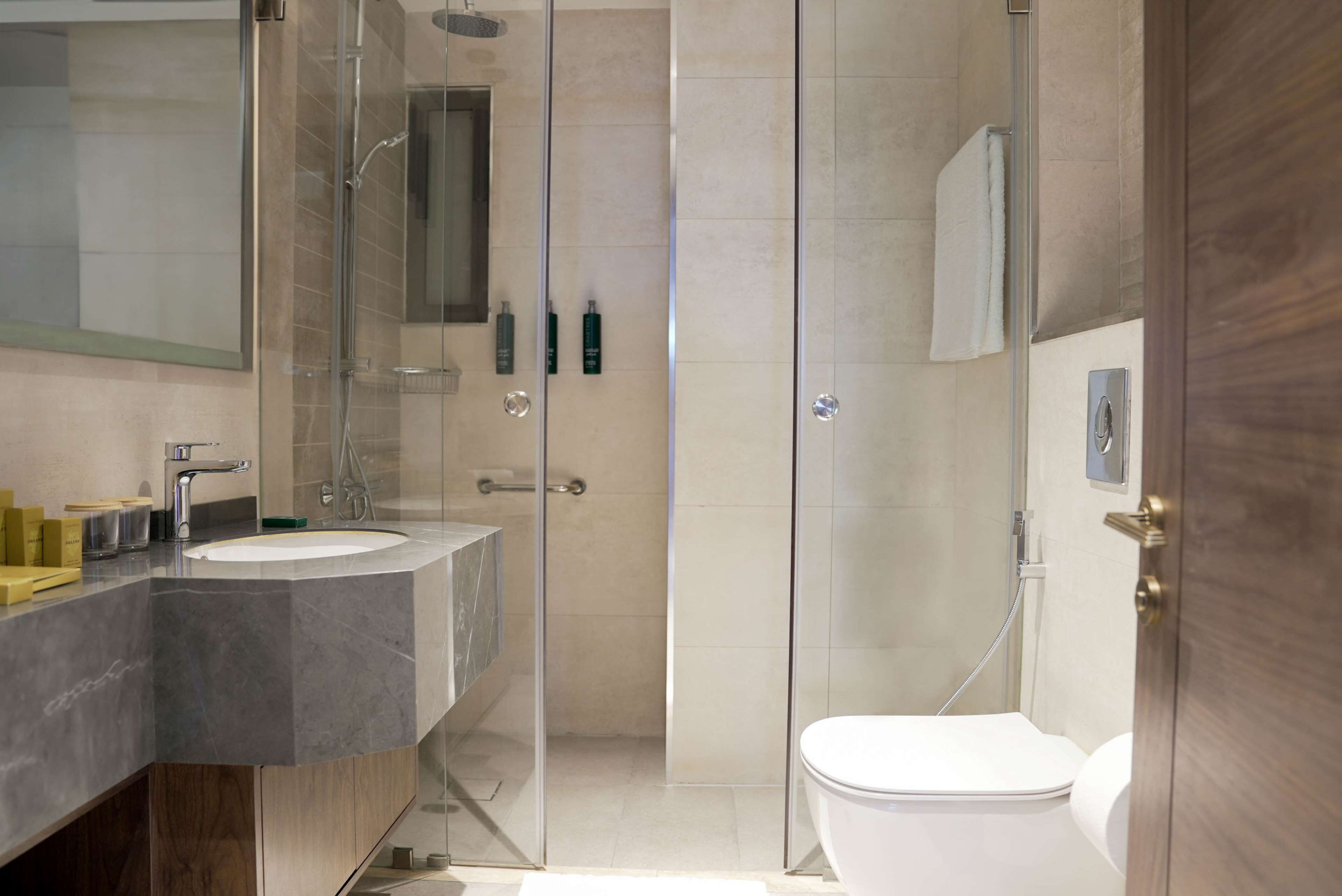 A modern bathroom with a glass-enclosed shower, a double sink vanity, and a toilet.