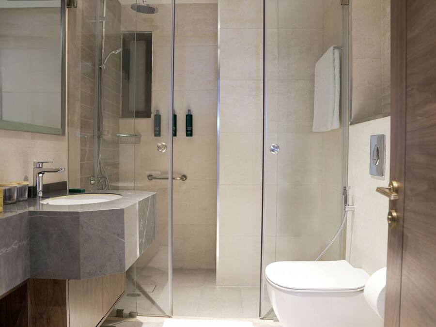 A modern bathroom with a glass-enclosed shower, a double sink vanity, and a toilet.