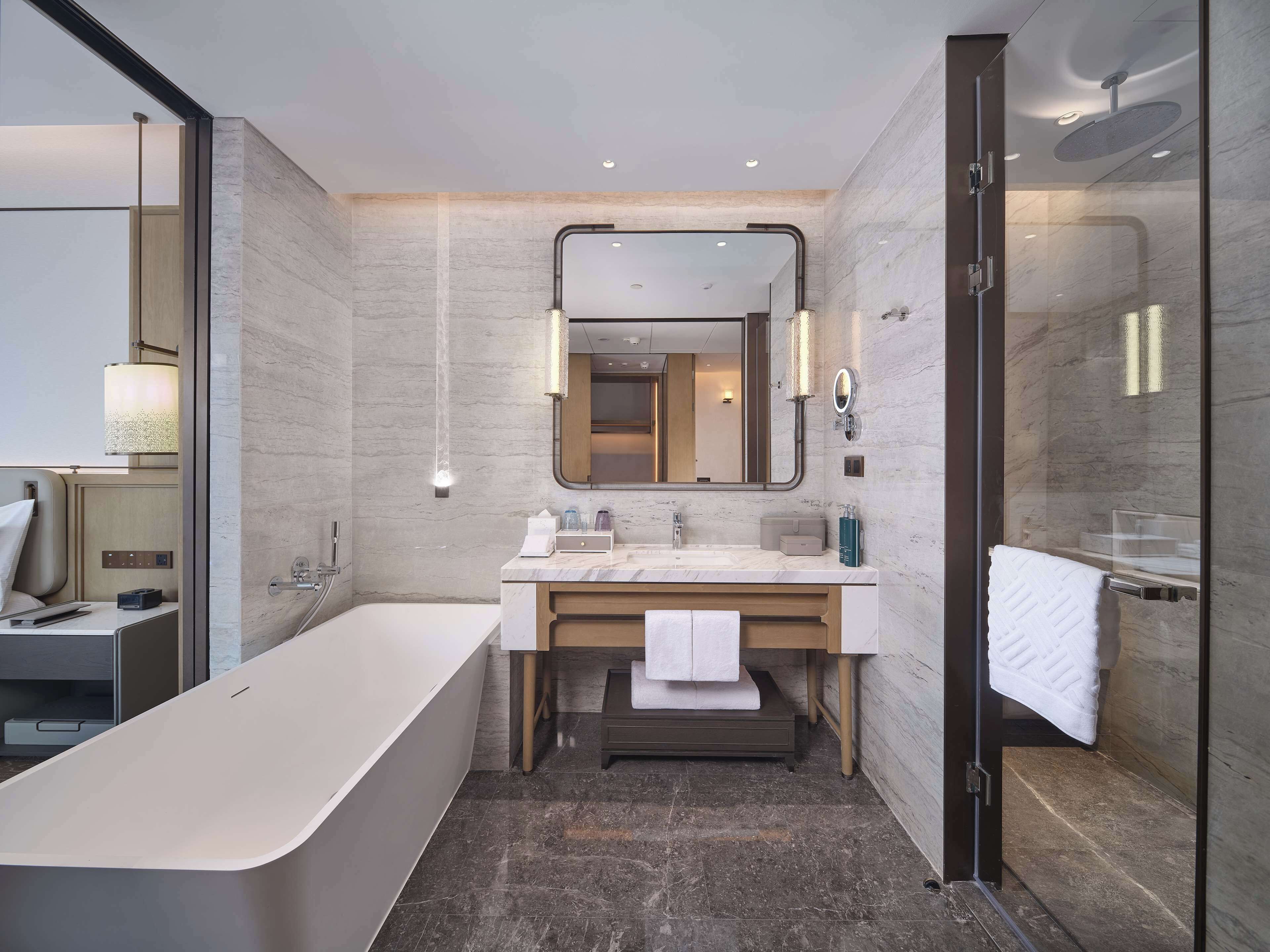 A modern bathroom with a freestanding bathtub, a large mirror, and a glass-enclosed shower area.