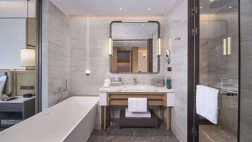 A modern bathroom with a freestanding bathtub, a large mirror, and a glass-enclosed shower area.