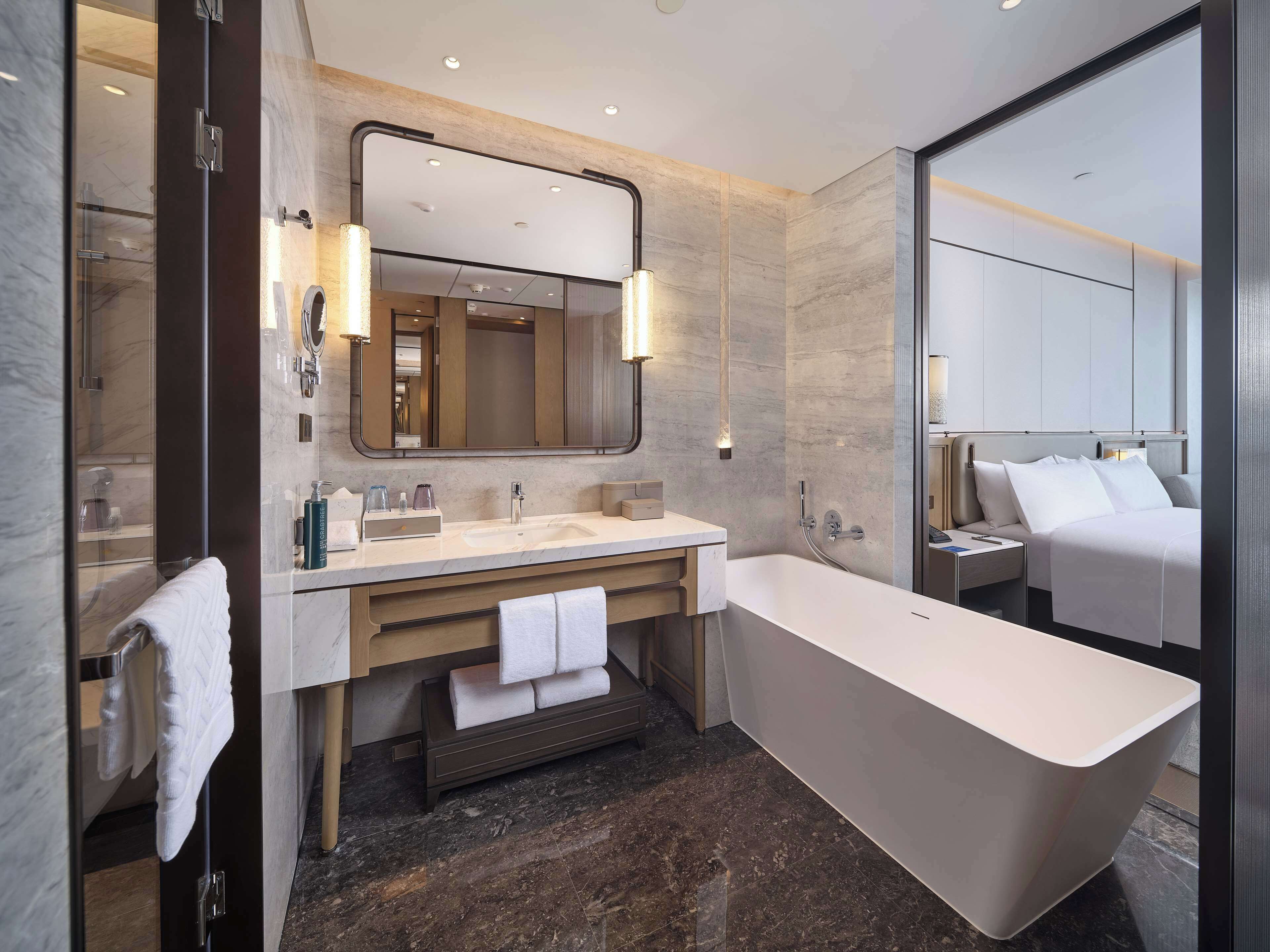 Un baño moderno con una bañera grande, un tocador con espejo y una zona de ducha separada.